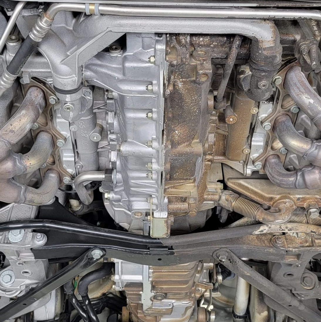 Dirty undercarriage showing contaminated transmission and suspension components before cleaning